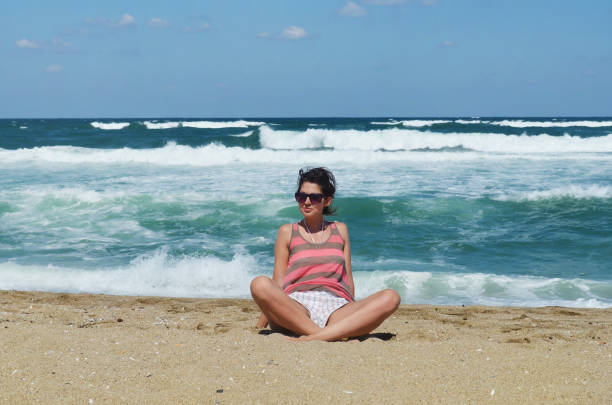 Woman sitting on a beach with big waves