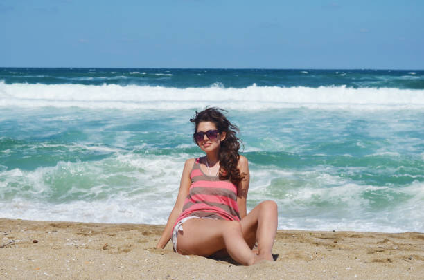Woman sitting on a beach with big waves