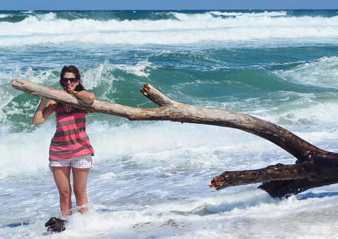 Woman sitting on a beach with big waves