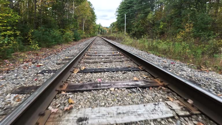 Fast low altitude FPV drone flight above railroad tracks through fall forest