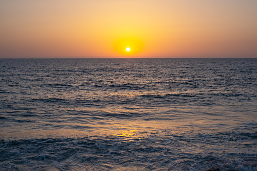 sun sets sky over the Mediterranean Sea horizon with a warm, golden glow. The sea's waves  magical tranquil seascape