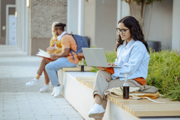 istock Young Latin female student using laptop on the bench on campus 2026129562