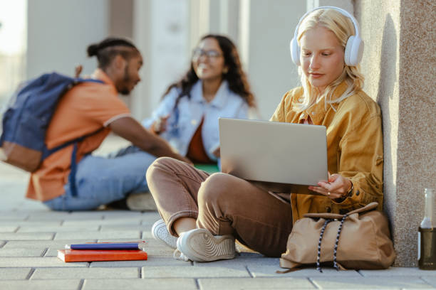 istock Young female student using laptop on the street 2026137041