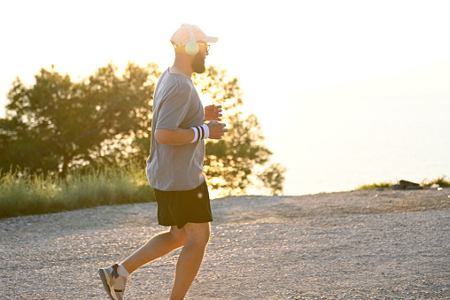 Man in sportswear runs along the sea with a view of the mountains