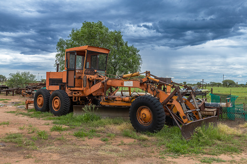 Orange grader parked on the side of a road, Namibia