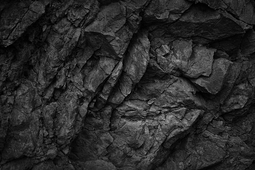 Black white dark gray rock stone basalt mountain granite volcanic texture background. Close-up. 3d. Cracked collapse, broken, crumbled.