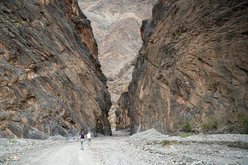 Two senior women, tourists, walking on spectacular road through Wadi Bani Awf. It is one of Oman’s most picturesque valleys.