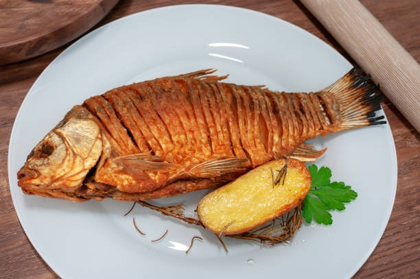 istock Fried crucian fish on wooden table garnished with potato. 2026188109