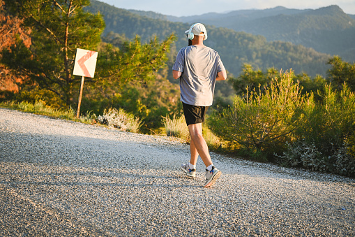 Man in sportswear runs along the sea with a view of the mountains