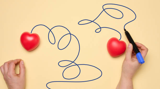 istock Two red hearts on a yellow background, a woman's hand draws a trajectory 2026219791