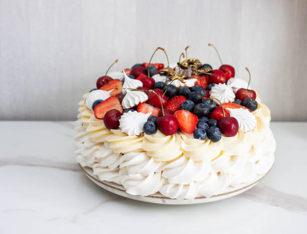 pavlova cake with whipped cream cheese, chocolate sauce, fresh strawberry, blueberry and raspberry, decorated with meringues on plain background - large cheese beautiful red zdjęcia i obrazy z banku zdjęć