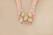 female hands in pearl bracelets hold painted Easter eggs decorated with beads
