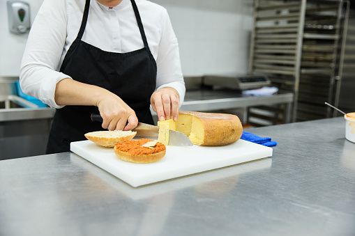 Female cook preparing sandwich in bakery kitchen. Sobrasada typical of Mallorca