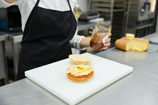 Female cook preparing sandwich in bakery kitchen. Sobrasada typical of Mallorca