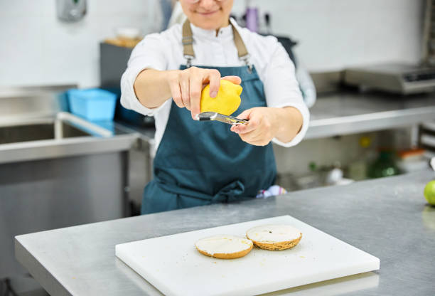 Female cook preparing sandwich in bakery kitchen.
