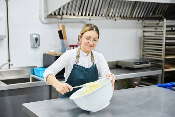istock Woman pastry chef beating dough with spatula while preparing a delicious cake in the kitchen of a pastry shop. 2026294104