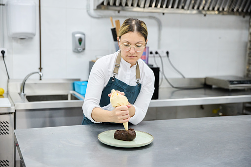 Female baker filling pastry with cream