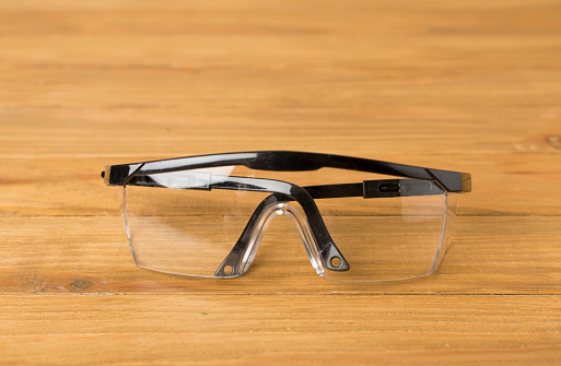 Blue safety glasses on wooden table