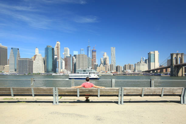 istock Young man sitting on a bench contemplating the Manhattan skyline 2026301853