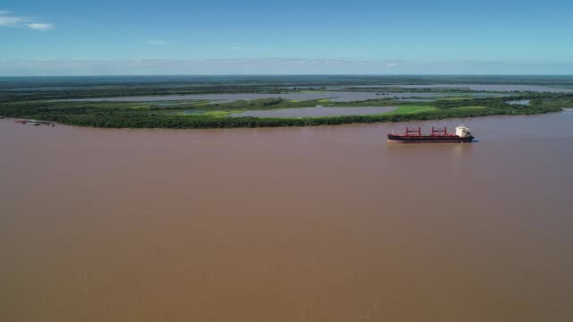 Cargo ships and grain terminal on a muddy river, clear sky, aerial view