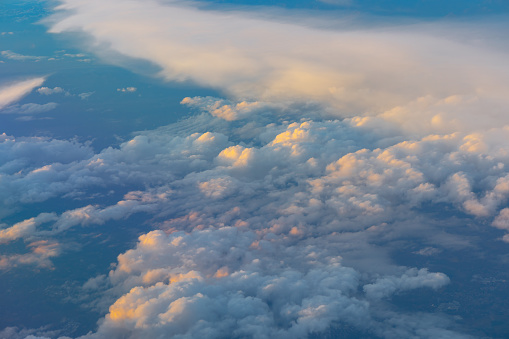 Sunlight through the clouds in the vast blue sky, viewed from the window of an aircraft