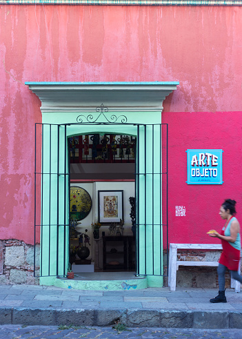 Oaxaca, Mexico: A woman walking past a colorful tourist shop in downtown Oaxaca.