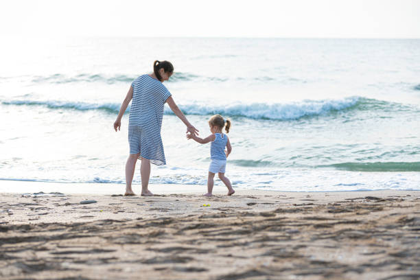 Mom with little girl playing on the beach at sunset.