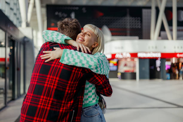 A happy woman is arrived from a journey and hugging her friend on a train station. An urban passenger arrived from a train trip and hugging her friend on train station. Young couple hugging at station