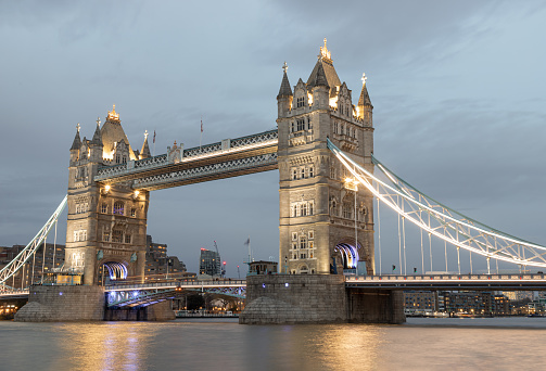 London, UK - Feb 15, 2024 - Beautiful scenery view of famous Tower bridge and skyline with reflections in the river thames just after sunset. The illuminated Tower Bridge, Space for text, Selective focus.