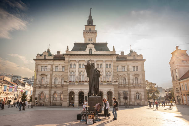 Picture of the central square of novi sad, Serbia, called Trg Slobode, with the city hall in background and pedestrians passing by and the svetozar miletic statue. Novi Sad is the second largest city in Serbia and the capital of the autonomous province of Vojvodina. It is located in the southern portion of the Pannonian Plain. The Monument to Svetozar Mileti in Novi Sad is a bronze statue located in Novi Sad , capital city of Vojvodina in Serbia . The work is included in the list of cultural monuments of great importance of the Republic of Serbia. It was designed by Ivan mestrovic in 1939.