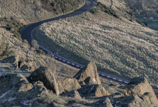 Edinburgh, Scotland - Jan 17, 2024 - A road going along the slope of mountain range on Arthur's Seat at Edinburgh city on a sunny day. Destinations in Europe, Space for text, Selective focus.