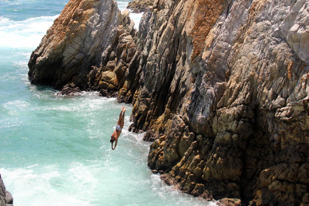 la quebrada is a 45 meter high cliff, in the mexican port where the famous dives are made by young people who climb - beach stone wall one person imagens e fotografias de stock