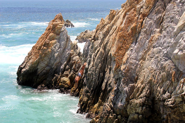 la quebrada is a 45 meter high cliff, in the mexican port where the famous dives are made by young people who climb - beach stone wall one person imagens e fotografias de stock