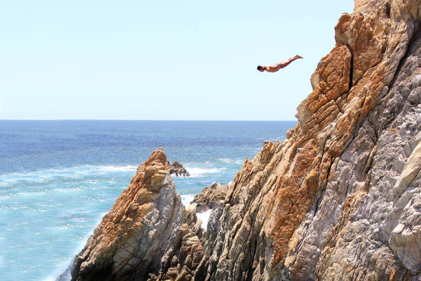 la quebrada is a 45 meter high cliff, in the mexican port where the famous dives are made by young people who climb - beach stone wall one person imagens e fotografias de stock