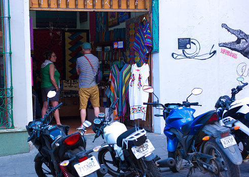 Oaxaca, Mexico: Tourists in a boutique in downtown Oaxaca; motorbikes and mopeds line the foreground.