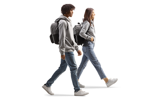 Full length profile shot of an african american male student and a caucasian female student walking isolated on white background