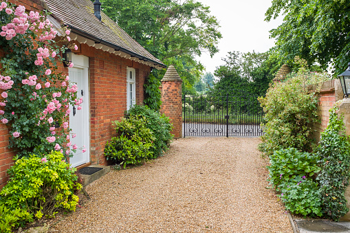 English country house and garden with a gravel driveway and wrought iron gates.