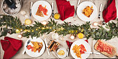 Food, breakfast and table with Christmas decoration for a festive family celebration feast. Event, juice and high angle of gourmet xmas brunch with salmon, eggs and bread on plate for holiday party.