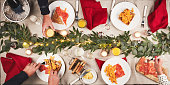 Food, breakfast and hands of people at table with Christmas decoration for a festive family celebration. Event, juice and high angle of gourmet brunch with bacon, eggs and bread for holiday party.