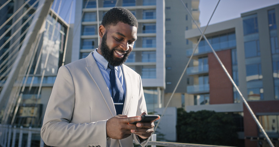 Business, smartphone and happy black man in city for social media, notification or reading email on app. Phone, smile and African professional in urban town, typing and advisor on internet outdoor