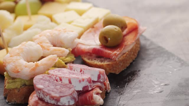 Italian or Spanish restaurant with traditional tapas food, Spanish cuisine, delicious tapas and cheese plate, bruschetta with cheese, olives dry tomatoes and tasty sandwich bar appetizer, buffet