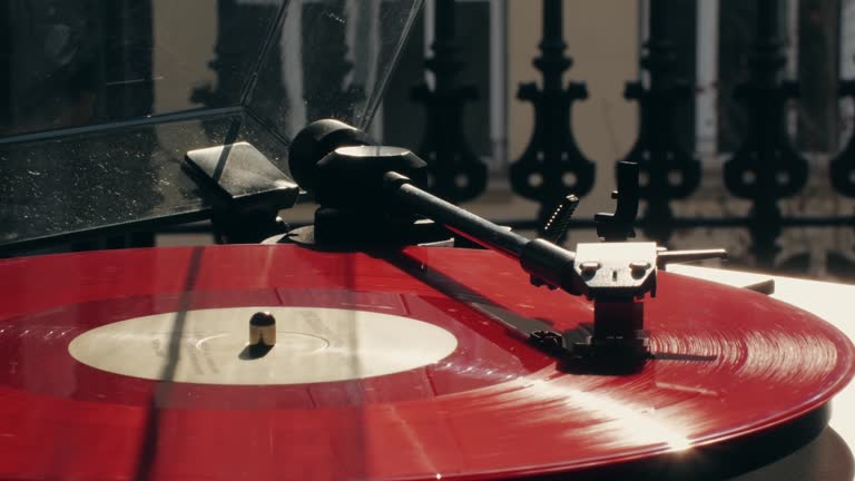 Retro Vinyl red record player playing music, close-up macro shot of vintage LP disc old phonograph spinning. Retro music player at home.