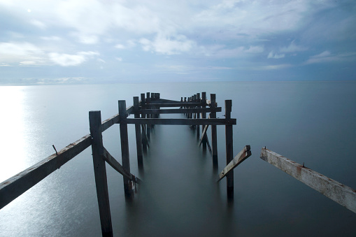 the ruins of a wooden bridge on the edge of the sea