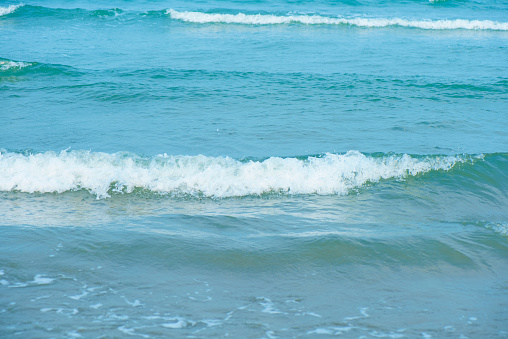 Waves on the beach. Blue sea wave. Blue water surface texture with ripples, splashes, and bubbles. Abstract summer banner background Water waves in sunlight with copy space cosmetic moisturizer.