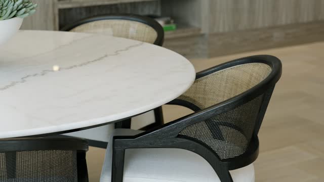 Close up of three stylish chairs with white seats and translucent backs standing by coffee table with plant on marble surface on background of interior with wooden flooring