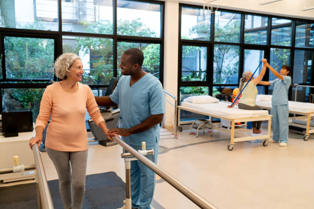 istock Caucasian senior patient smiling while looking at black male therapist before starting her workout leaning on parallel bars at a physical recovery center 2026614968