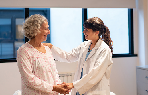Latin American female doctor holding her senior patientâs hands while smiling at a nursing home - Emotional support concepts