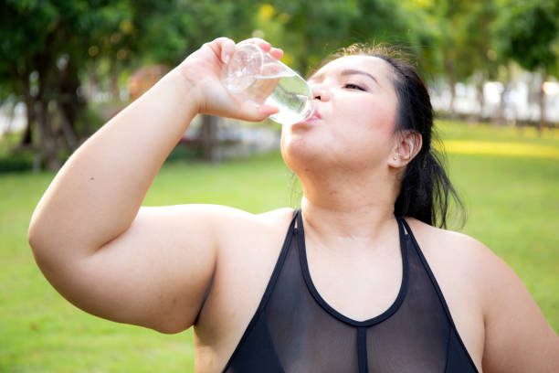 istock Active plus size woman hydration drinking a water bottle outdoors, taking a break during a sunny day exercise routine, fat woman drinking water after workout in garden, activity for health. 2026617653