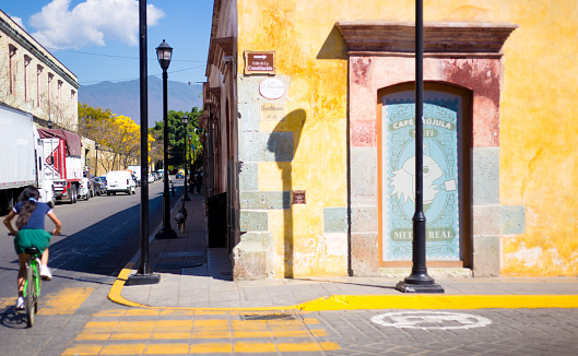 Oaxaca, Mexico: A cyclist rides past a colorful building in downtown Oaxaca.