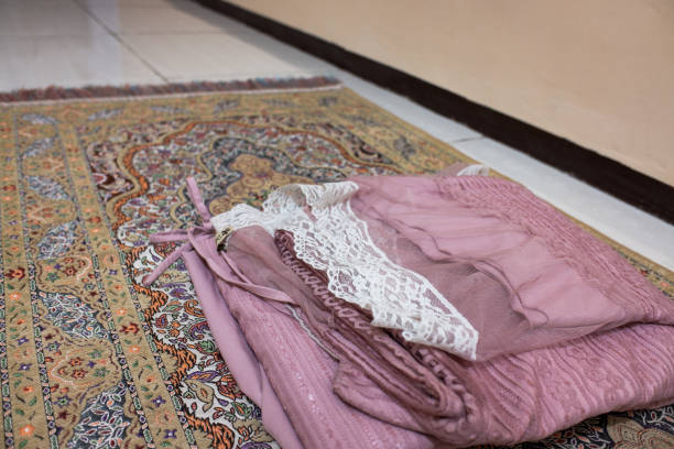 a pink mukena folded over a prayer mat, a prayer tool.